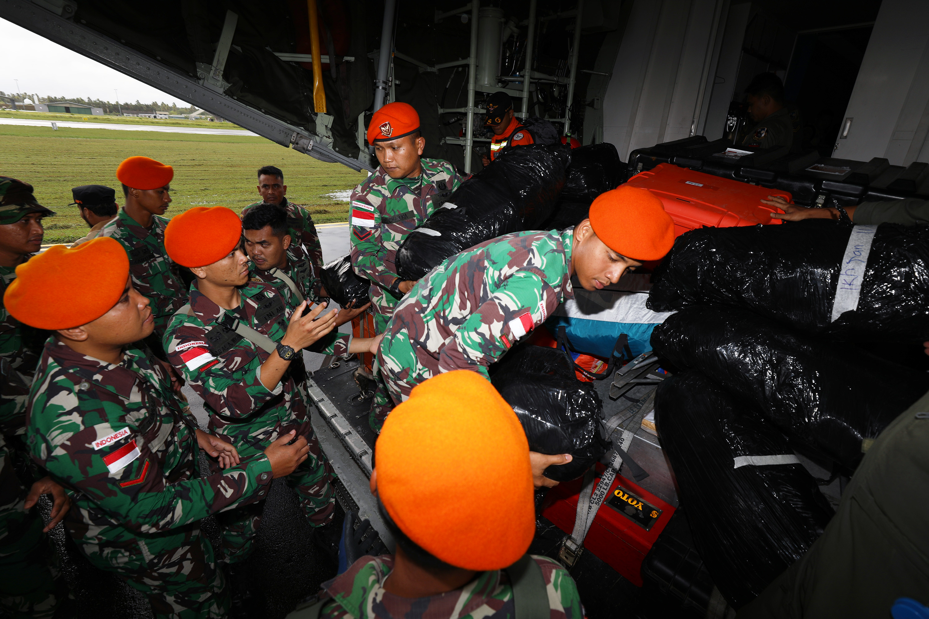 Anggota Kopasgat TNI AU menurunkan logistik dan peralatan BNPB dari pesawat Hercules C-130 sesaat setelah tiba di Lanud Raden Sadjad Ranai, Natuna, Selasa (7/3).